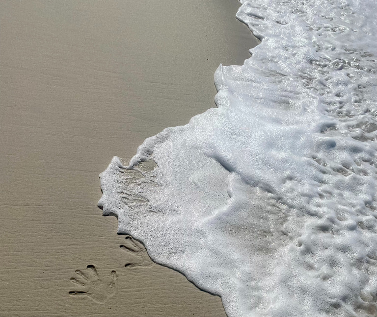 plage avec trace de mains et vagues